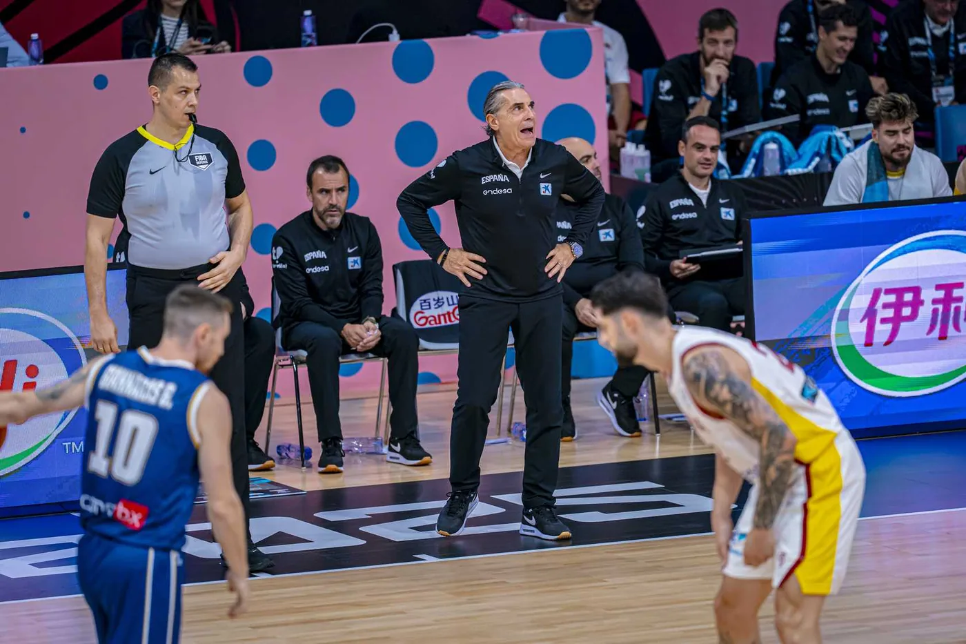 Cuerpo técnico en banquillo durante un partido internacional de baloncesto